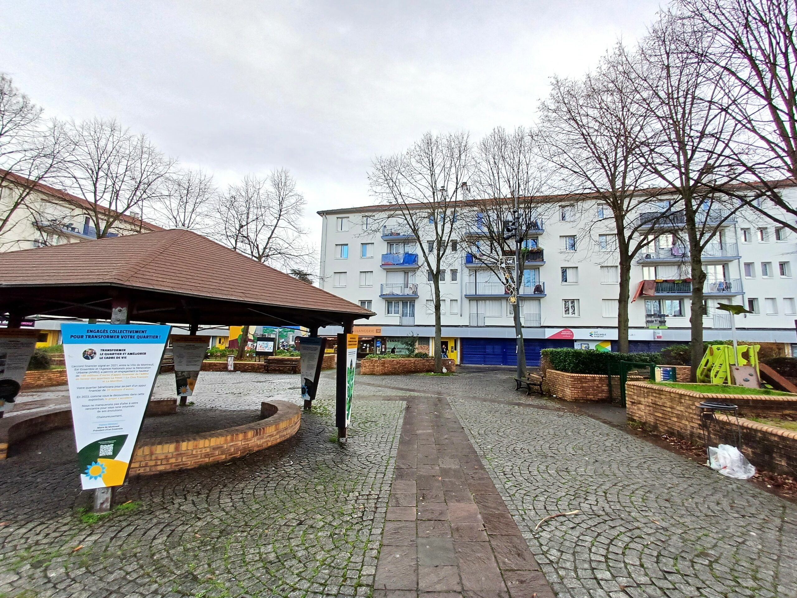 Place avec immeuble derrière et arbres